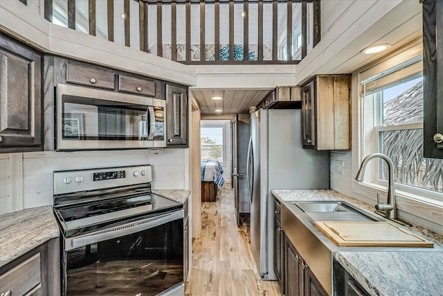 kitchen featuring appliances with stainless steel finishes, sink, dark brown cabinets, and light hardwood / wood-style flooring