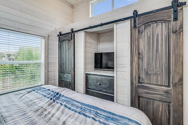 bedroom with wood walls and multiple windows