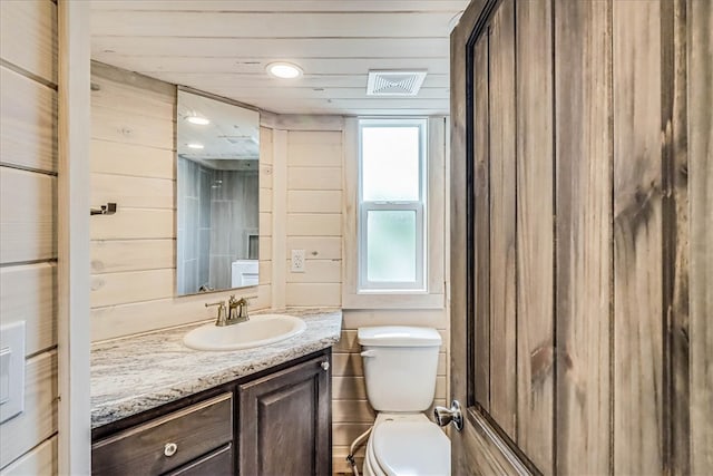 bathroom with wood walls, toilet, and vanity