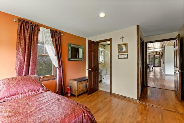 bedroom with hardwood / wood-style floors and ensuite bath