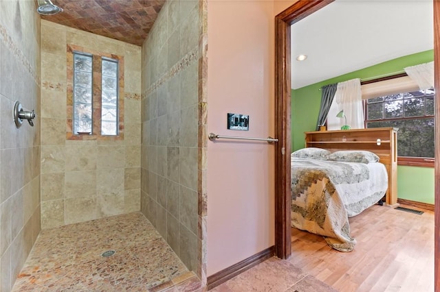 bathroom with wood-type flooring, lofted ceiling, and tiled shower