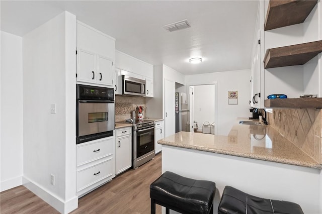 1406 Hwy 72, Three Rivers, TX 78071 - kitchen with open shelves, appliances with stainless steel finishes, tasteful backsplash, a peninsula, and white cabinets