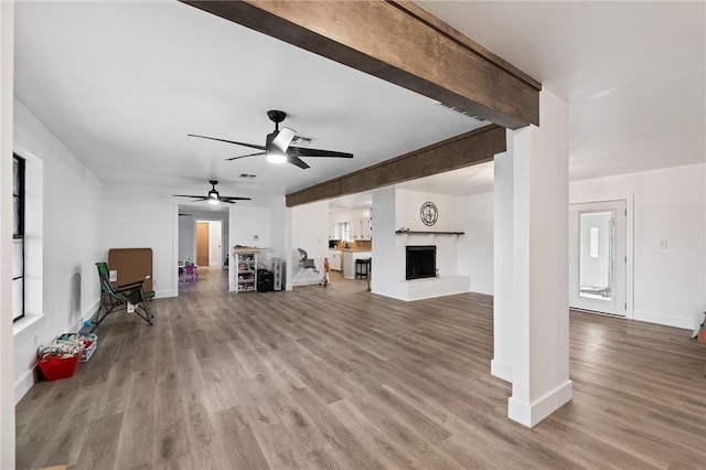 1406 Hwy 72, Three Rivers, TX 78071 - unfurnished living room with wood finished floors, a fireplace with raised hearth, and a ceiling fan