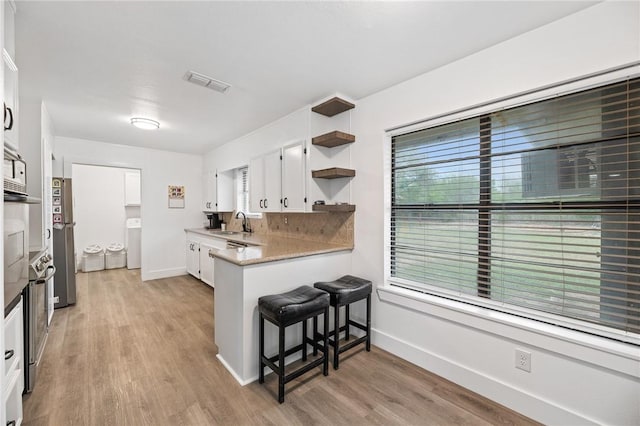 1406 Hwy 72, Three Rivers, TX 78071 - kitchen with open shelves, a breakfast bar, light wood finished floors, and white cabinetry