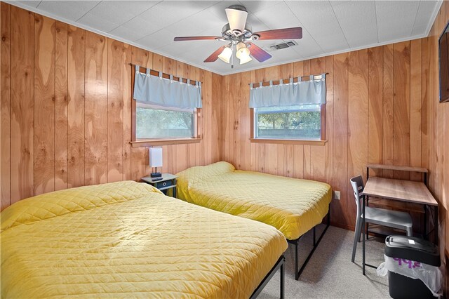 carpeted bedroom with wood walls, ceiling fan, and ornamental molding