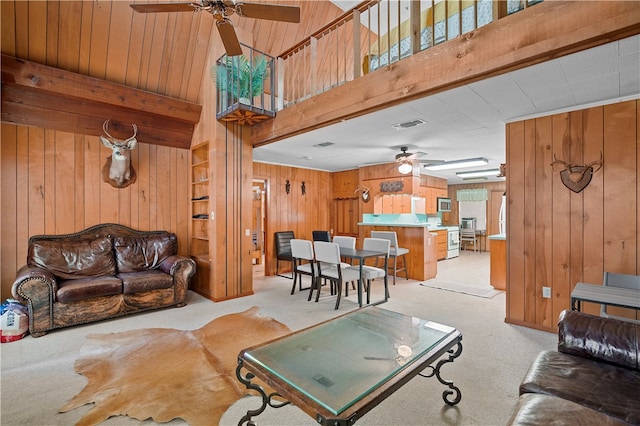 living room featuring light colored carpet, wood walls, and ceiling fan