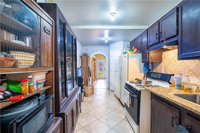 kitchen featuring sink, a textured ceiling, light tile patterned floors, backsplash, and white range oven