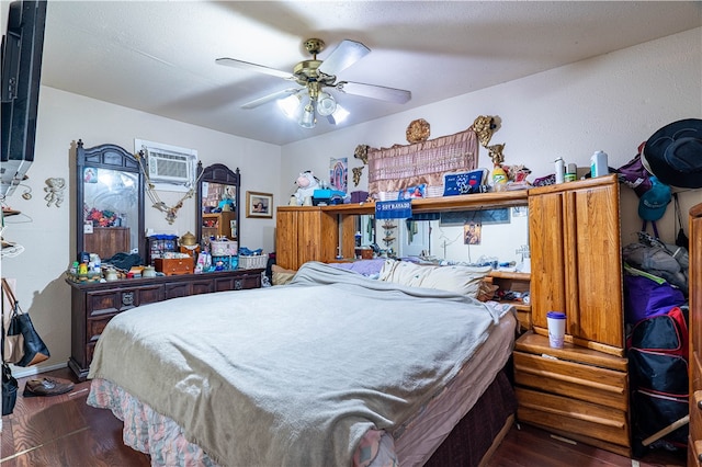 bedroom with a wall unit AC, ceiling fan, and dark hardwood / wood-style flooring