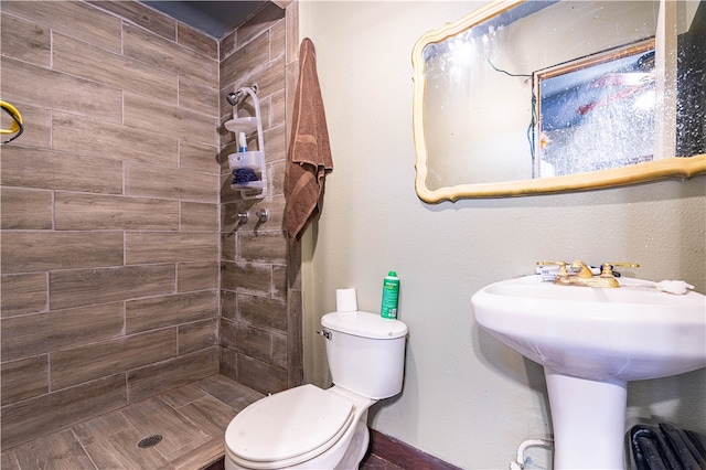 bathroom featuring toilet, sink, and tiled shower