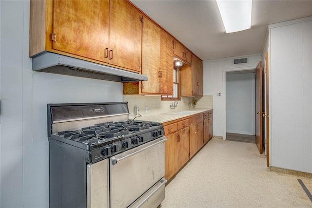 3730 Fort Worth St, Corpus Christi, TX 78411 - kitchen with stainless steel gas range, under cabinet range hood, light countertops, and brown cabinetry
