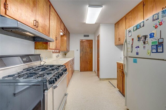 3730 Fort Worth St, Corpus Christi, TX 78411 - kitchen with freestanding refrigerator, gas range oven, under cabinet range hood, light countertops, and a sink