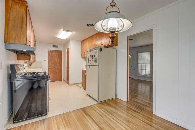 3730 Fort Worth St, Corpus Christi, TX 78411 - kitchen with freestanding refrigerator, range with gas stovetop, light wood-style floors, under cabinet range hood, and brown cabinetry