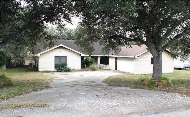 ranch-style house with central air condition unit and a garage