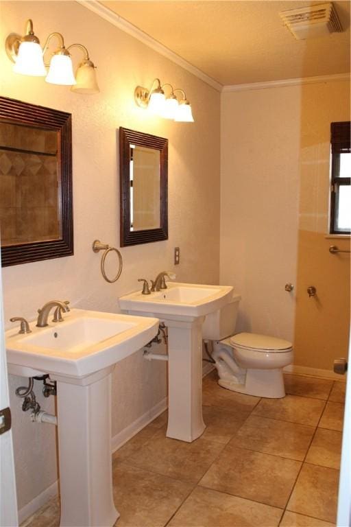 bathroom with tile patterned floors, crown molding, double sink, and toilet