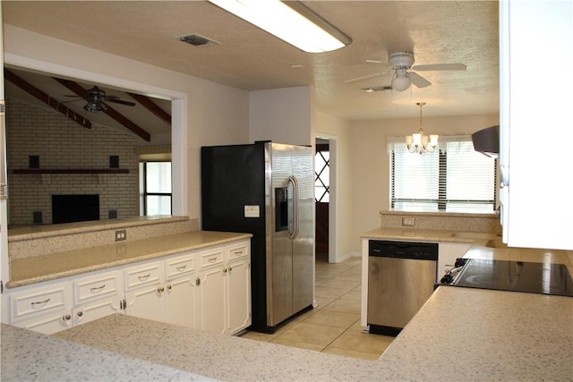 kitchen with appliances with stainless steel finishes, light tile patterned flooring, pendant lighting, ceiling fan with notable chandelier, and white cabinets