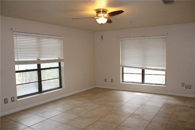 tiled spare room with ceiling fan and a healthy amount of sunlight