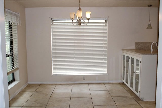 unfurnished dining area with a notable chandelier and light tile patterned floors