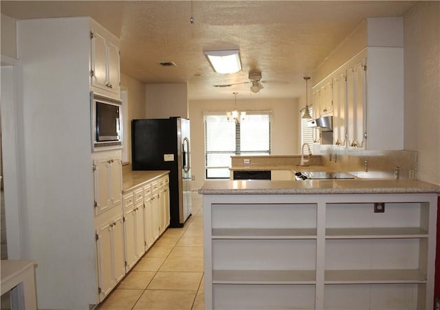 kitchen with light tile patterned flooring, white cabinetry, decorative light fixtures, black appliances, and kitchen peninsula