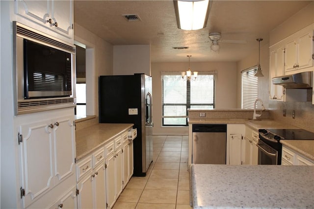 kitchen featuring white cabinets, appliances with stainless steel finishes, pendant lighting, and light tile patterned floors