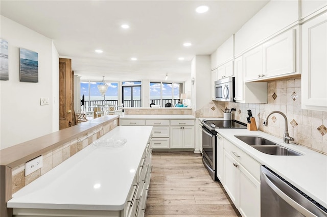 kitchen featuring white cabinets, decorative backsplash, light hardwood / wood-style flooring, sink, and appliances with stainless steel finishes