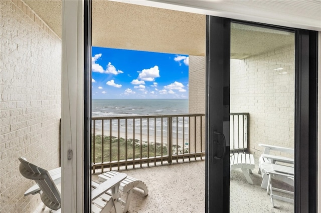 balcony featuring a view of the beach and a water view