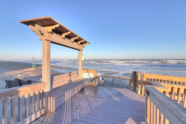 view of property's community with a beach view and a deck with water view