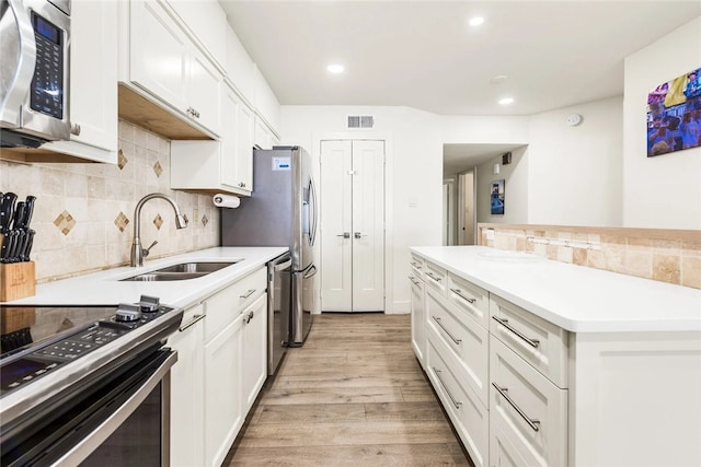 kitchen featuring stainless steel appliances, white cabinetry, sink, and light wood-type flooring