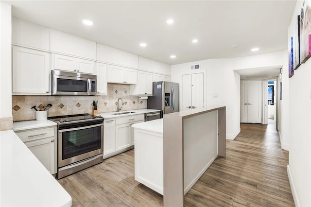 kitchen with a center island, white cabinets, light hardwood / wood-style floors, and stainless steel appliances