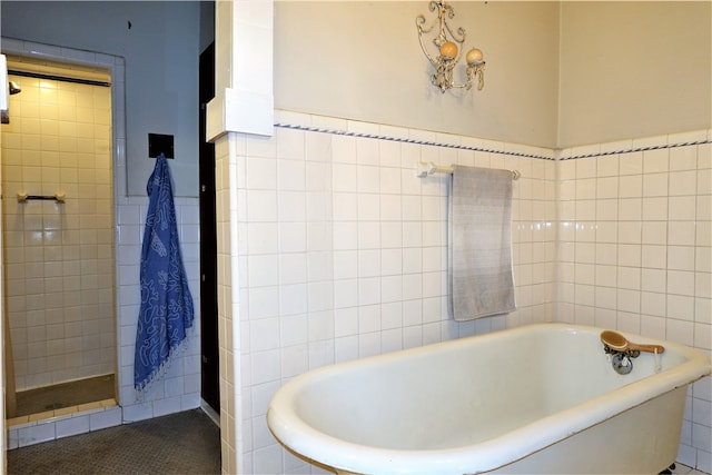 bathroom with shower with separate bathtub and tile walls