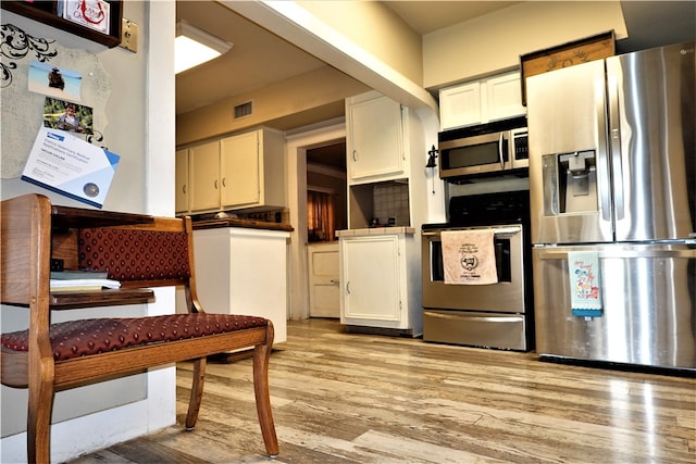 kitchen with white cabinetry, light hardwood / wood-style flooring, and appliances with stainless steel finishes