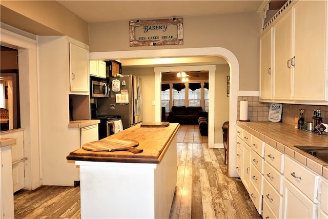 kitchen featuring white cabinetry, appliances with stainless steel finishes, backsplash, tile counters, and light hardwood / wood-style flooring