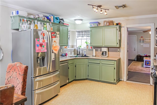 kitchen with ornamental molding, sink, appliances with stainless steel finishes, and green cabinetry