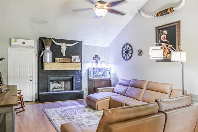 living room with vaulted ceiling, light hardwood / wood-style floors, a brick fireplace, a wall unit AC, and ceiling fan