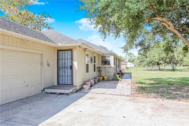 doorway to property featuring a garage and a lawn