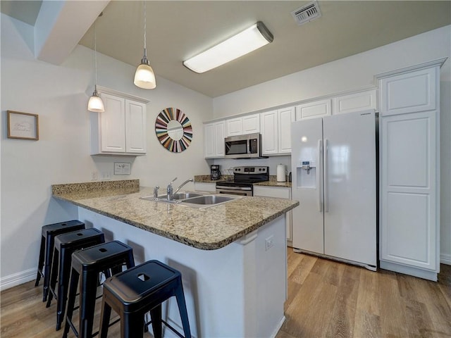 15017 Beach Walk Loop, Corpus Christi, TX 78418 - kitchen featuring appliances with stainless steel finishes, a sink, light wood-style flooring, and a kitchen breakfast bar