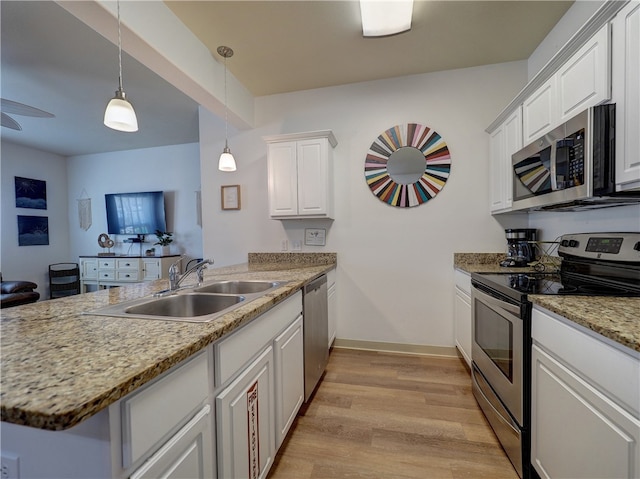 kitchen featuring stainless steel appliances, white cabinetry, light wood-type flooring, pendant lighting, and sink