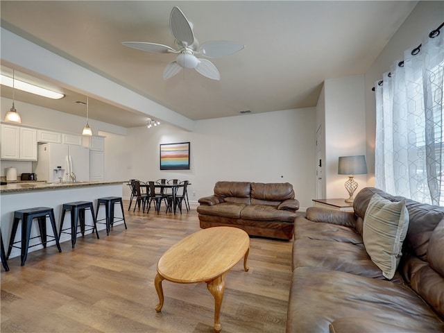 living room with ceiling fan and light hardwood / wood-style flooring