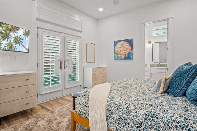 bedroom featuring connected bathroom, sink, access to exterior, and light wood-type flooring