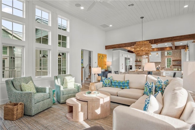 living room with wood ceiling, beam ceiling, ceiling fan with notable chandelier, and a towering ceiling