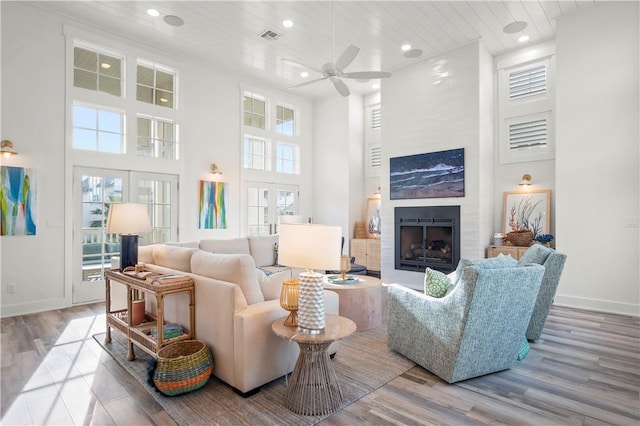 living room with hardwood / wood-style floors, a towering ceiling, french doors, and ceiling fan