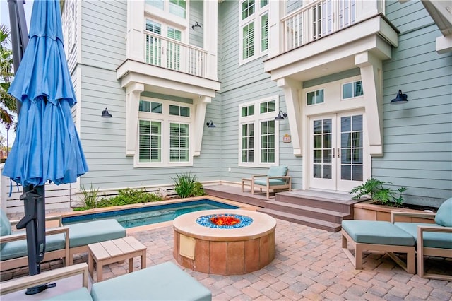 view of patio featuring french doors, a balcony, and a fire pit