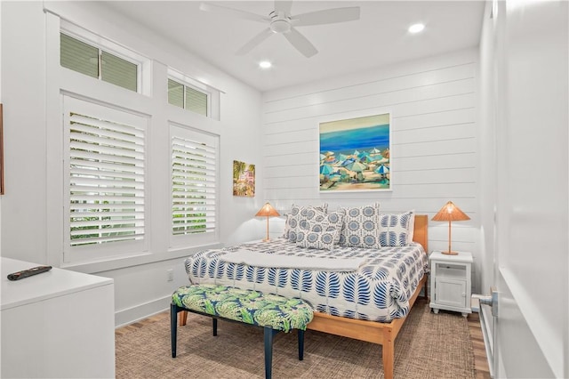 bedroom featuring hardwood / wood-style flooring, ceiling fan, and wood walls