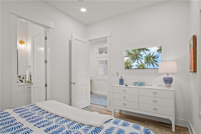 bedroom with connected bathroom and hardwood / wood-style floors