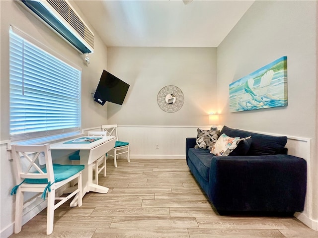 living room with an AC wall unit and light wood-type flooring