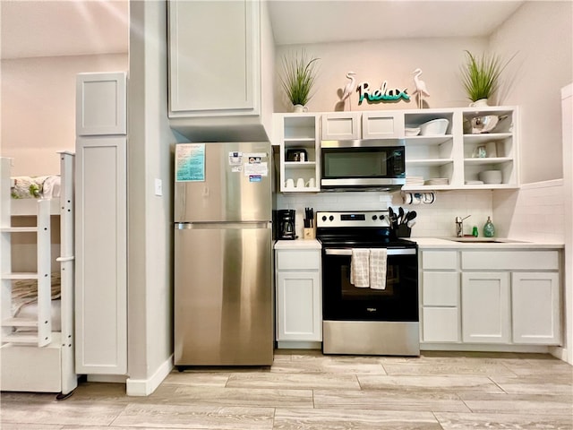 kitchen featuring light hardwood / wood-style flooring, appliances with stainless steel finishes, decorative backsplash, and white cabinets