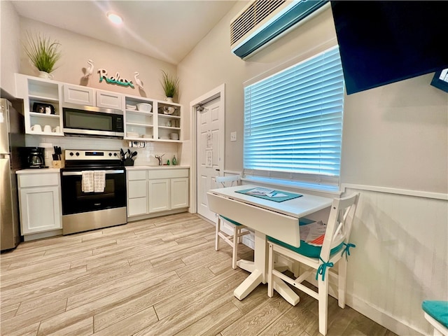 kitchen featuring white cabinets, light hardwood / wood-style floors, backsplash, and appliances with stainless steel finishes