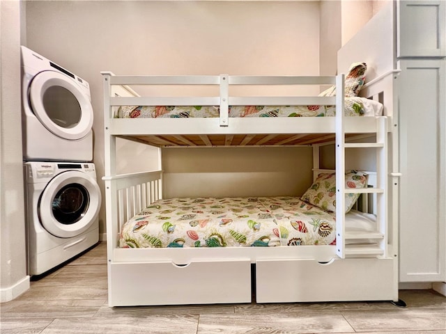 bedroom featuring stacked washer and clothes dryer and light hardwood / wood-style flooring