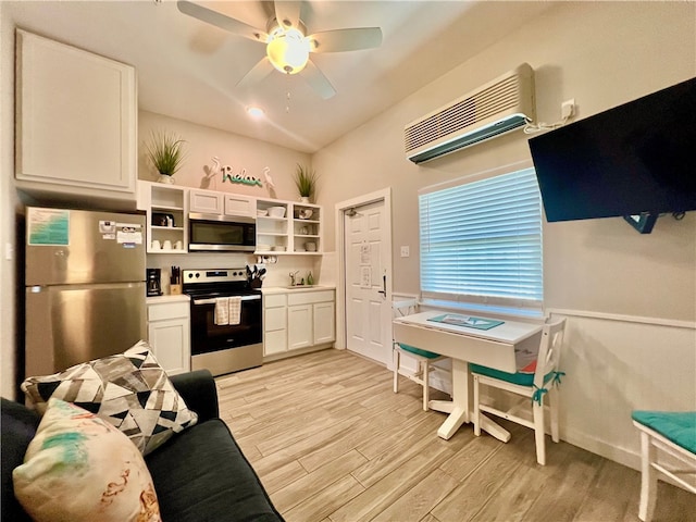 kitchen with a wall unit AC, stainless steel appliances, light hardwood / wood-style floors, white cabinets, and ceiling fan