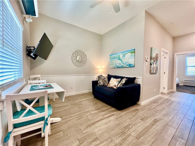 living room featuring lofted ceiling, ceiling fan, and light hardwood / wood-style flooring