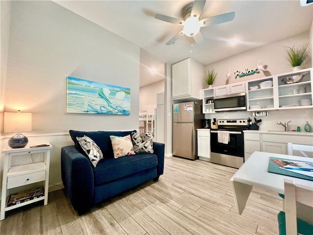 kitchen featuring stainless steel appliances, decorative backsplash, sink, white cabinetry, and light wood-type flooring